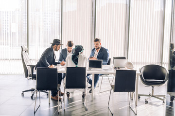 Business meeting between multiracial upper management board members in the new modern office conference room with panoramic windows and laptop.