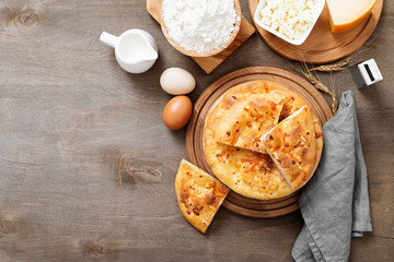 Freshly baked khachapuri with cheese on a wooden table.
