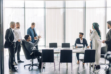 Hot debates. Group interracial business partners disagree with company CEO dressed Arab, on contract terms, people have dispute , using lots of hand gestures, but staing positive meeting in office