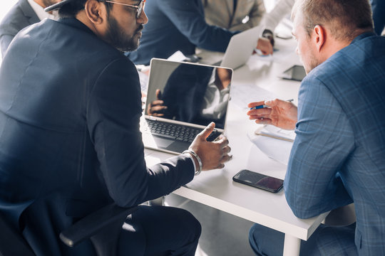 Close Up Top View Of Confident Business Men Of Different Race And Ages, Working Together, Man Looking On Blueprint, Talking, Using Laptop Duting Meeting In The Office