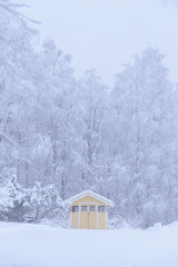 The yellow house in the forest has covered with heavy snow and bad sky in winter season at Tuupovaara, Finland.