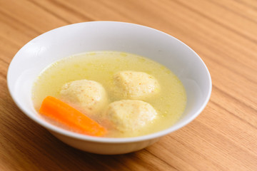 Traditional matzoh ball (kneidlach) soup.White bowl with authentic matzo ball chicken taste hot soup ( bouillon ) tradition Jewish food for Passover and every day.