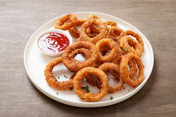 Delicious golden battered, breaded and deep fried crispy onion rings with ketchup.