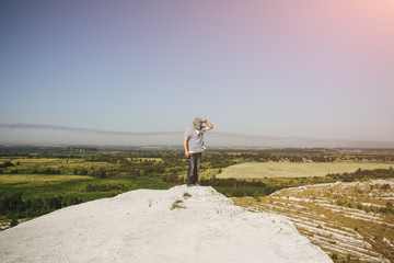 Man is standing on the white hill and looking at the landscape view with the green field. White hills and mountains. Nature and travel concept. Wild and abandoned place.