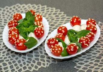 Cocktail tomatoes with mayonnaise, basil and mozarella on a white plate