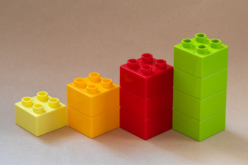 Obraz premium Growing bar chart from color toy blocks on beige background.