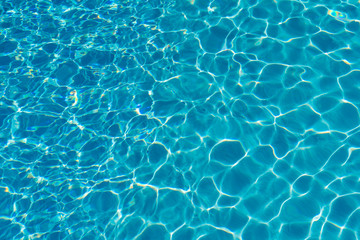 Fototapeta na wymiar Blue water in swimming pool background. Ripple Water in swimming pool with sun reflection. Blue swimming pool rippled water detail.
