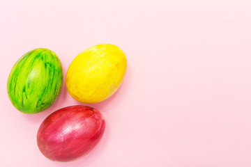 Easter Eggs on pink background.Yellow green and maroon eggs handmade new style of colouring form flower on a colored cardboard. Pattern, easter concept, trendy colors