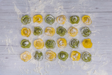Homemade fresh Italian ravioli pasta on white wood table  background,top view.