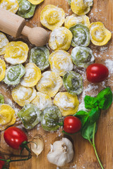 Homemade fresh Italian ravioli pasta on wood table  with flour, basil,tomatoes,background,top view.