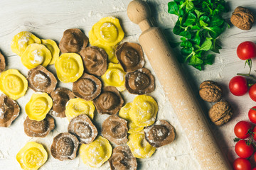 Homemade fresh Italian ravioli pasta on white wood table  with flour, basil, tomatoes,background,top view.