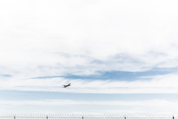 Airplane taking off behind barbwire security fence. 