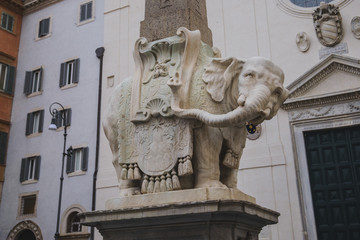 Tourists seated on the Elephant and Obelisk sculpture in Piazza della Minerva in Rome