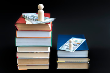 concept of education and income. Wooden figures dollars and books on a black background.