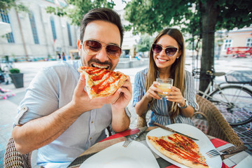 Couple eating pizza snack outdoors.They are sharing pizza and eating.
