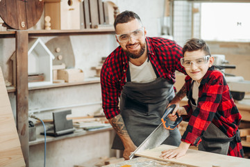 Experienced male teacher of carpentry skill acquaints a boy, with art of woodworking. Together with...