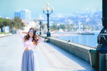 Girl walking along the seafront in dress in hot summer day