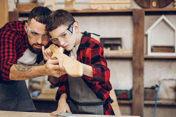 Fatherhood, hobby, carpentry, woodwork and people concept - Father and little son wearing...