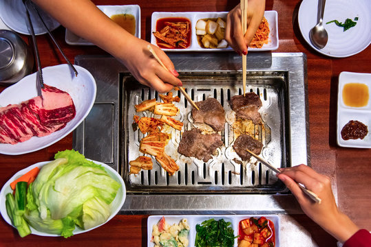 People having Korean barbeque and vegetables
