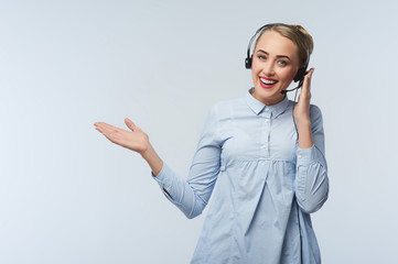 Portrait of cheerful young support phone operator in headset, with copyspace area