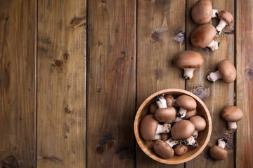 Champignon mushrooms, sacking mat and spices on wooden background. Wooden dishes. Photo in a rustic style. Place for text.