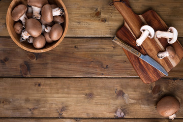 Champignon mushrooms, sacking mat and spices on wooden background. Wooden dishes. Photo in a rustic style. Place for text. The concept of a village photo.