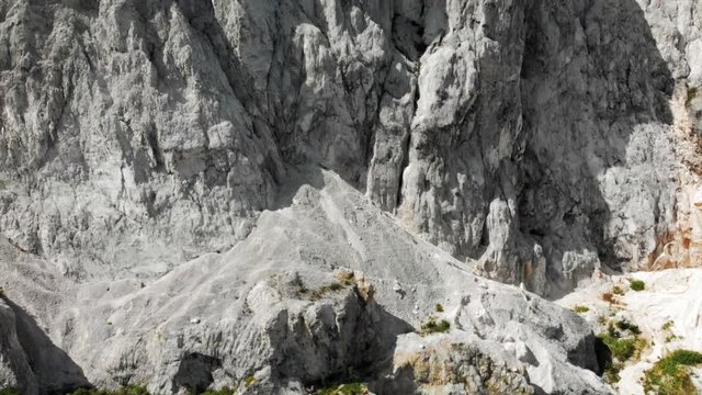 Aerial View Panning Up White Rocky Cliffs to Green Mountaintop