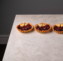 homemade cherry tartlets, on a grey marble backdrop, dark background