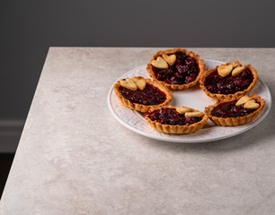homemade cherry tartlets, on a grey marble backdrop, dark background