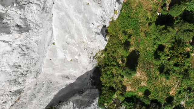 Aerial View Panning Above White Rocky Cliff & Green Valley Floor
