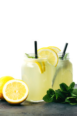 Refreshing lemonade drink with lemon slice and mint in the jar on dark table and white background