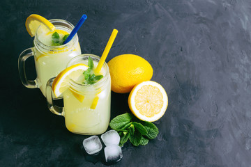 Refreshing lemonade drink with lemon slice and mint in the jar on dark background