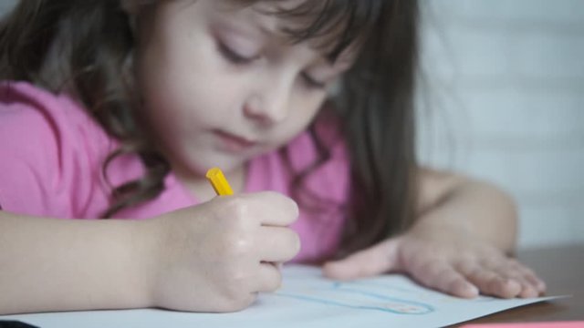 The child draws. Adorable little girl is writing in a notebook. Preschooler training.