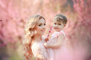 Mom with an infant in the rose garden with flowers trees