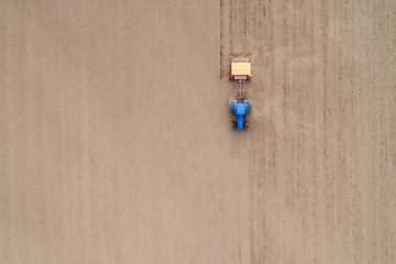 A blue tractor plows the field. Spring season.