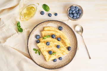 Two pancakes with blueberries and mint on plate, top view