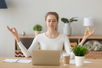 Young woman student taking break meditating at home office desk