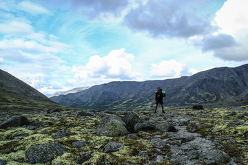 Majestic and cold northern nature: rocks, moss and heavy clouds and a small figure of a tourist man