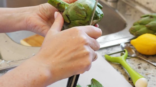 Woman peeling artichokes. Cooking process at modern kitchen