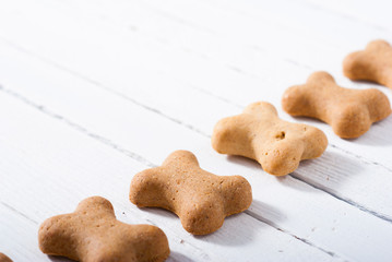 bone shape dog biscuits on white wood background