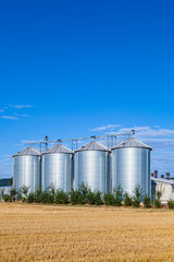 four silver silos in the field after the harvest