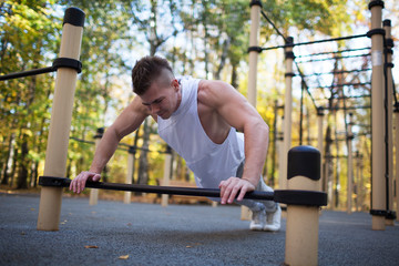 fitness, sport, training and lifestyle concept - young adult fit man doing push-ups outdoors