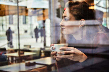 Girl daydreaming while holds a coffee cup at local coffee shop
