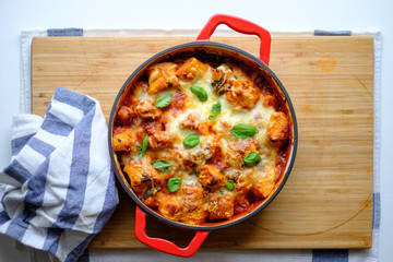 Homemade gnocchi baked in tomato sauce with spinach, toasted cheese on and fresh basil on top.