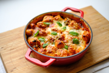 Homemade gnocchi baked in tomato sauce with spinach, toasted cheese on and fresh basil on top.