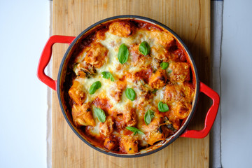 Homemade gnocchi baked in tomato sauce with spinach, toasted cheese on and fresh basil on top.