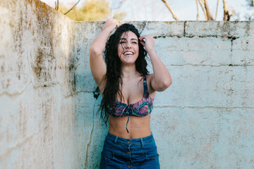 Smiling young brunette woman with bikini in an old empty pool
