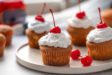 Homemade muffin with cream and cherry.