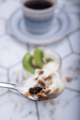 Breakfast homemade yogurt with kiwi and grains in glass served with coffee in the morning