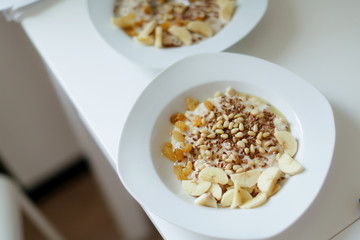 Bowl of oatmeal porridge with banana, blueberries, almonds, coconut and caramel sauce on teal rustic table, hot and healthy food for Breakfast, top view, flat lay